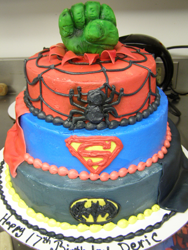 Superhero-themed birthday cake with bold colors and action figure toppers